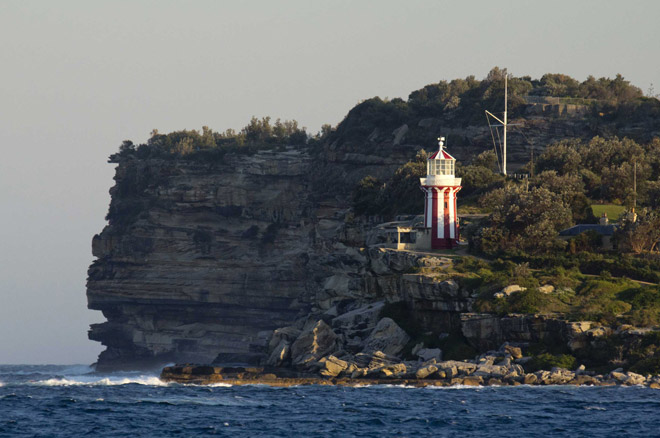 Hornby Lighthouse perched on the tip of South Head beside a World War II bunker. The lighthouse is painted in red and white vertical stripes to differentiate from Macquarie Light, several kilometres south. Walk around it on the South Head and Watsons Bay Walk.